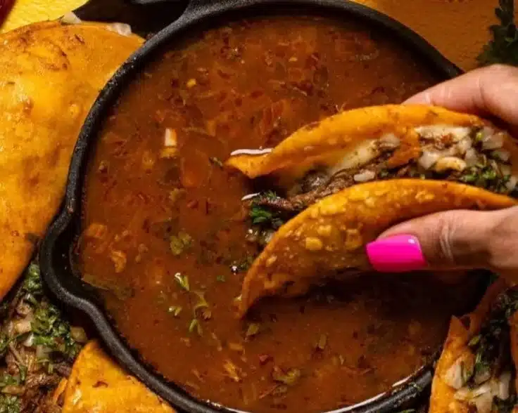 Delicious Birria Tacos served with consome and fresh toppings