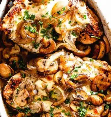 Cheesy baked chicken topped with mushrooms, served on a plate