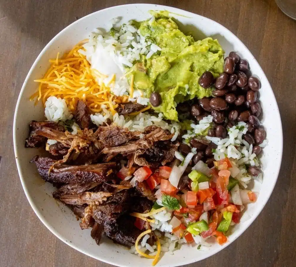 A delicious shredded beef burrito bowl topped with fresh vegetables and spices.