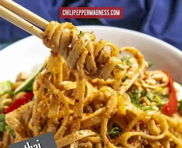 Bowl of Thai peanut noodles topped with fresh vegetables and peanuts